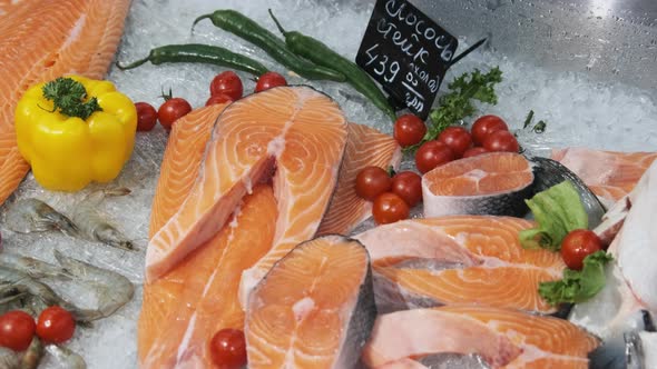 Composition of Trout and Salmon Steaks Lies on Ice in Showcase of Supermarket alt
