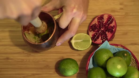 Barman swirling crushed lime cocktail fruit drink on wooden counter. alt