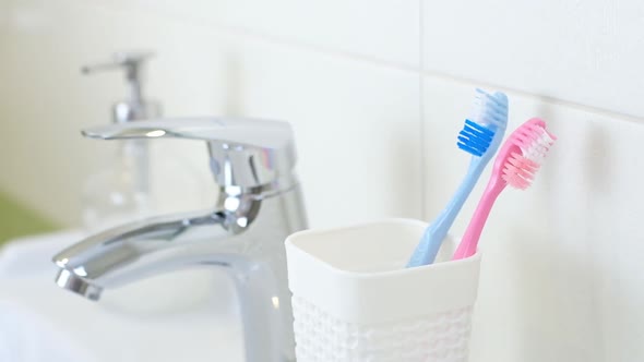 Woman Changing Old Brushes for New Modern Ultrasonic Toothbrush in Bathroom at Home alt