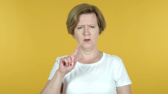 Old Woman Waving Finger To Refuse Isolated on Yellow Background alt
