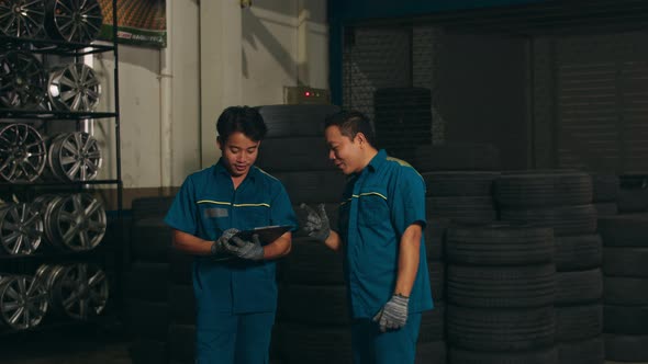 Two professional car mechanic using paperwork makes the oil and engine check to the car on lifted .