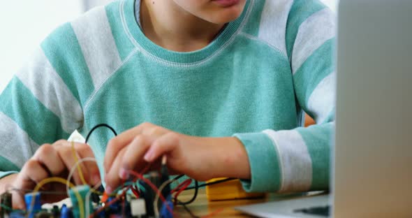 Schoolboy working on electronical project in classroom alt