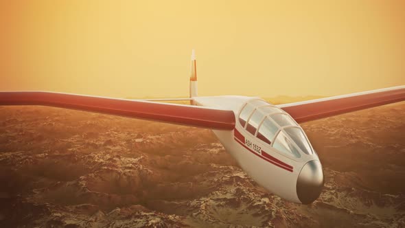 The white sailplane calmly gliding in the sky over the snow-covered mountains. alt