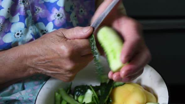 Closeup Elderly 80s Woman Hands Cut Cucumber Peels with Knife