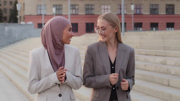 Smiling Young European Caucasian Female Manager Communicating with Indian Girl in Hijab Colleague alt