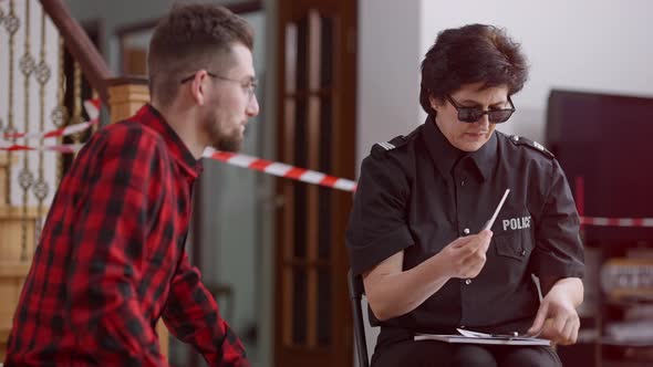 Police Officer in Sunglasses Showing Photos of Suspects to Concentrated Victim or Witness at Crime alt