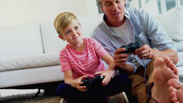 Father and son playing video game in living room 4k alt