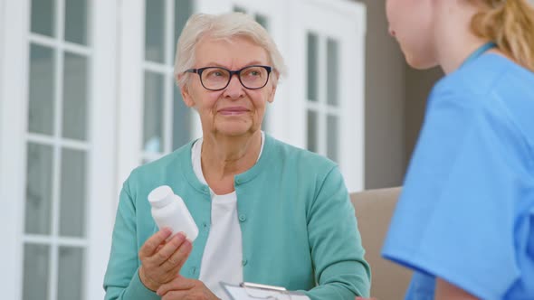 Senior patient woman with glasses holds pills bottle alt