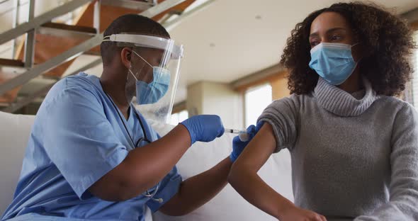 African american female doctor wearing face mask vaccinating african american patient alt