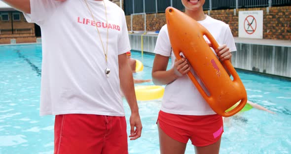 Swim coaches standing with inflatable floater near poolside alt