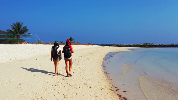Beautiful women happy together on exotic coast beach voyage by blue lagoon and bright sand backgroun alt