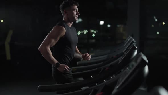 Cinematic Light Young Athletic Man Run on a Treadmill Aerobic Exercise and Endurance Training in the alt