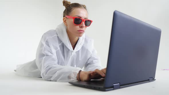 An Attractive Female Surfing Internet on Laptop in a White Room
