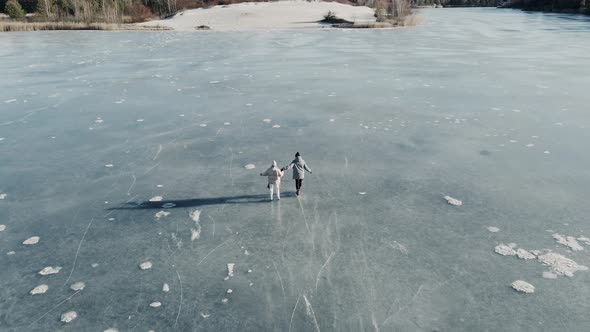 Aerial Shot of Couple Skating on a Frozen Lake in Beautiful Sunny Landscape