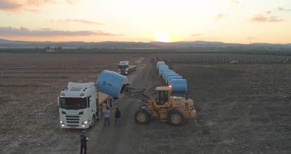 Aerial view of a tractor loading cotton bales on truck, Israel. alt