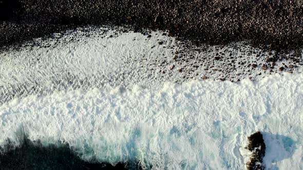 Aerial Top Down View of Waves Foaming on Rocky Coastline