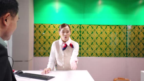 4K Asian businessman get boarding pass at check in counter in airport terminal. alt