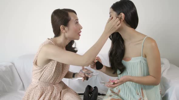 MS Young woman applying makeup and talking with friend