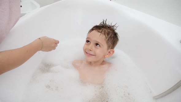 Mother Applying Shampoo and Washing Head of Her Son in Bath alt