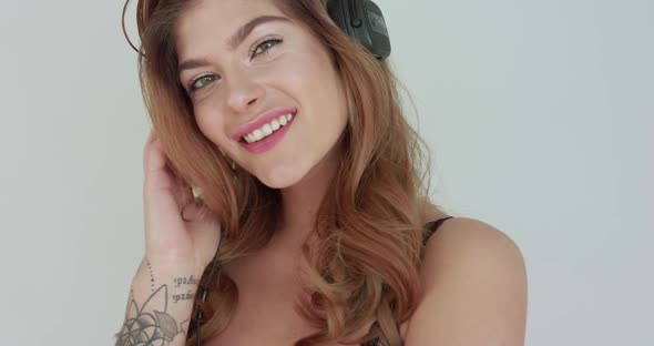 Lady Listening to Music in Headphones Touching One Earcup Dances and Flirts alt