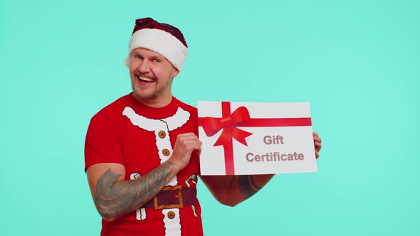 Man in Red Tshirt Santa Christmas Hat Presenting Card Gift Certificate Coupon Voucher for Winner alt