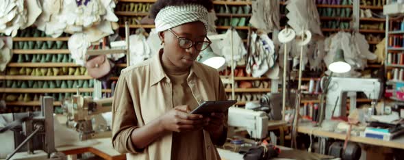 African American Woman Working on Tablet in Shoemaker Workshop alt