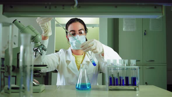 Scientist in Laboratory Doing Chemical Experiment with Blue Liquid in Test Tubes alt