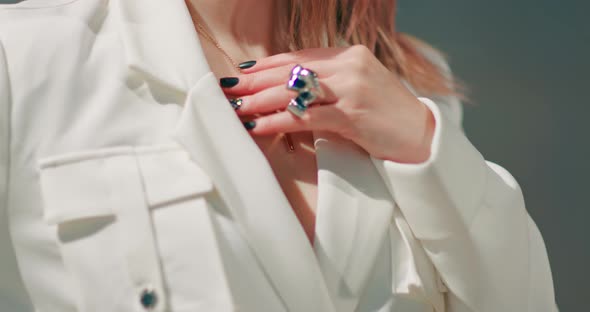 Close Up Model in Trendy White Jacket with Stylish Ring Touching Her Necklace alt