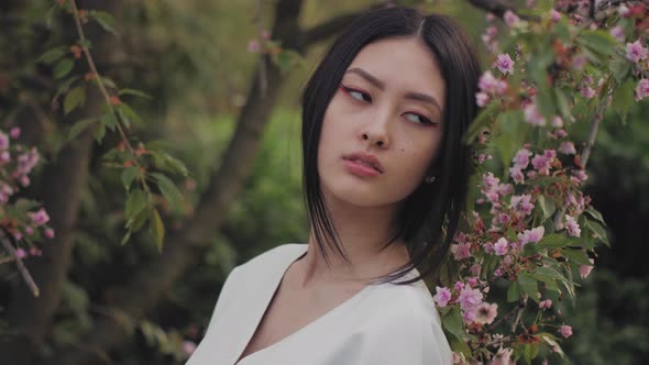 Asian Woman Outdoors on Spring Against Flower Blossom alt
