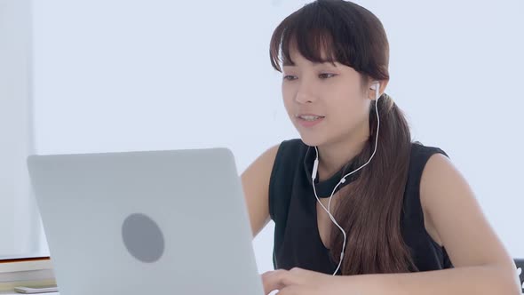 Young asian woman smiling sitting using laptop computer listening music with earphone for relax. alt