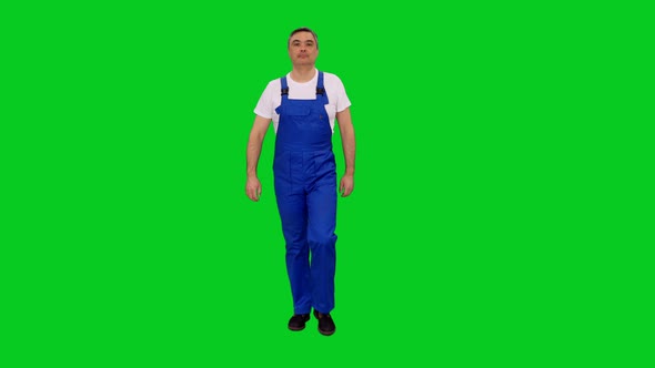 Adult Foreman In Blue Coveralls Walking Towards The Camera