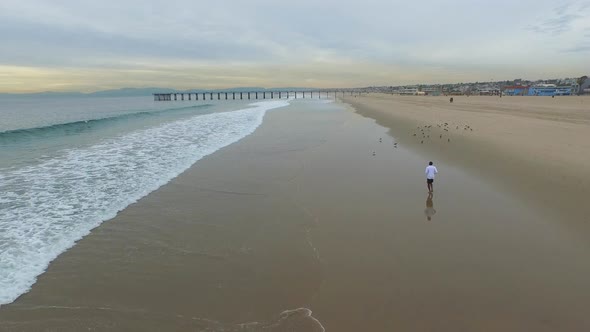 Aerial shot of young man running on the beach. alt
