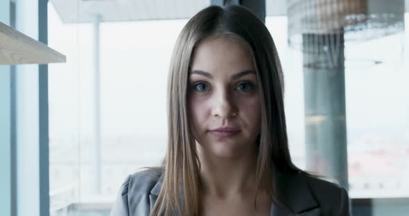Portrait of Young Attractive Female Who Looking at the Camera on the Office Near Window. Cheerfully alt