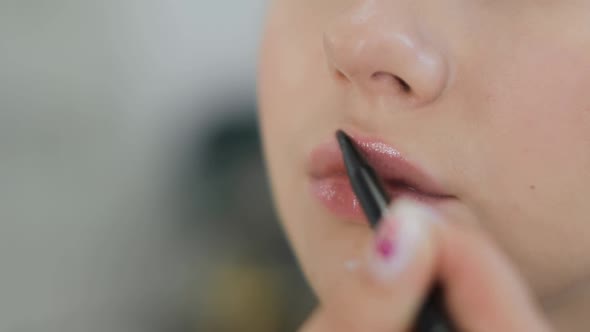 Makeup Artist Is Applying Nude Shade Lipglow To Young Woman Closeup View