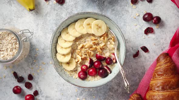 Ceramic Bowl of Oatmeal Porridge with Banana Fresh Cranberries and Walnuts alt