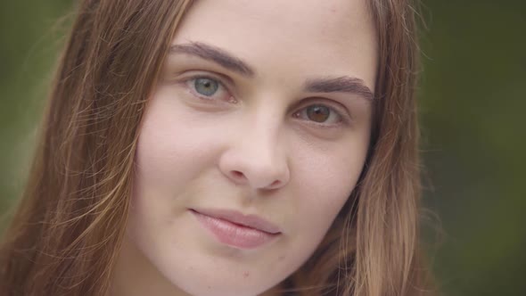 Close-up Portrait of Pretty Carefree Young Woman with Different Colored Eyes Looking at Camera alt