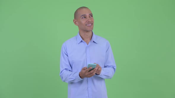 Happy Bald Multi Ethnic Businessman Thinking While Using Phone and Calling alt