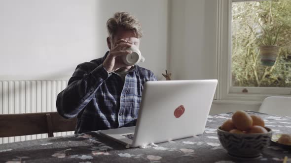 Mature Adult male working at home on laptop in kitchen