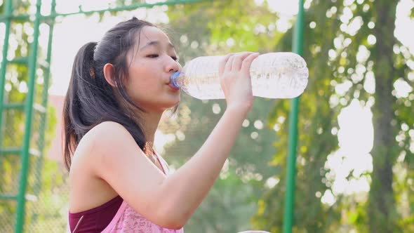 Healthy Asian sport woman drinking water after workout