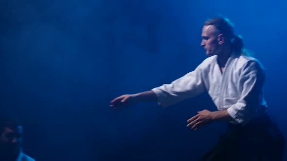 Fight Between Two Aikido Fighters in Dark Studio with Smoke and Lighting. Slow Motion. Close Up. alt