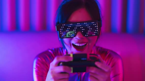 Young asian woman is using virtual reality headset. Neon light studio portrait alt