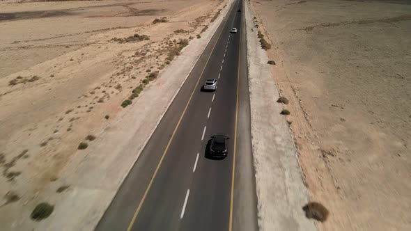 Car Driving on Asphalt Road Through the Desert Sands of the Blue Sky White Clouds