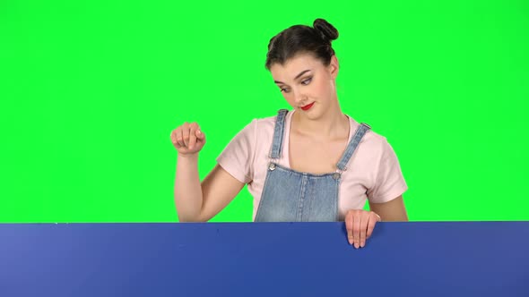 Girl Looking Out From Behind Blue Blank Placard Looks at Him and Shakes His Head Disapprovingly or alt