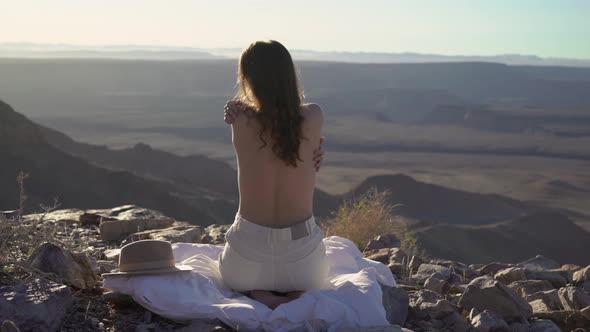 Young Woman Sitting Topless on Blanket at Edge of Fish River Canyon in Namibia