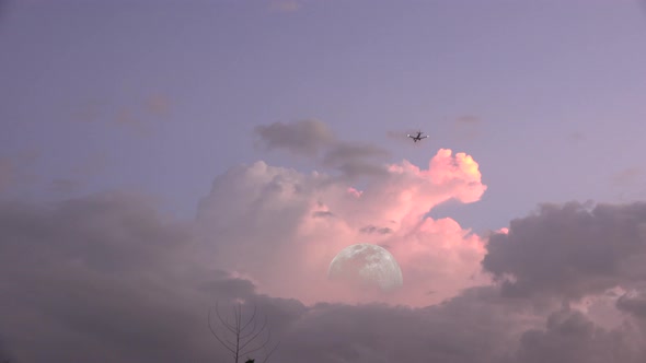 Over the moon, airplane flies over the moon in an evening sky.