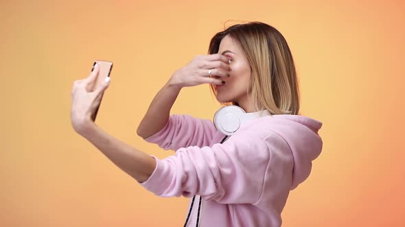 Woman Taking Selfie on Orange Background