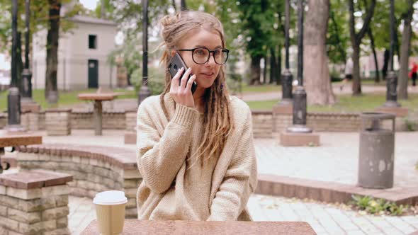 Smiling Hipster Girl Talking By Mobile in Park alt