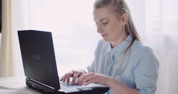 Smiling Woman Working on Laptop at Home Office. Businesswoman Typing on Computer Keyboard. alt