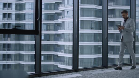 Focused Entrepreneur Using Tablet Researching Corporate Data in Office Building alt