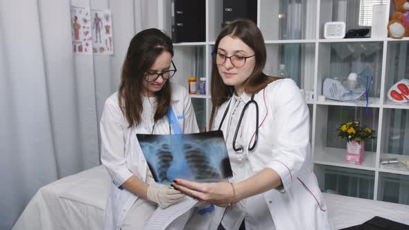 Two Female Doctor Examine Xray Images of the Patient in the Examining Room